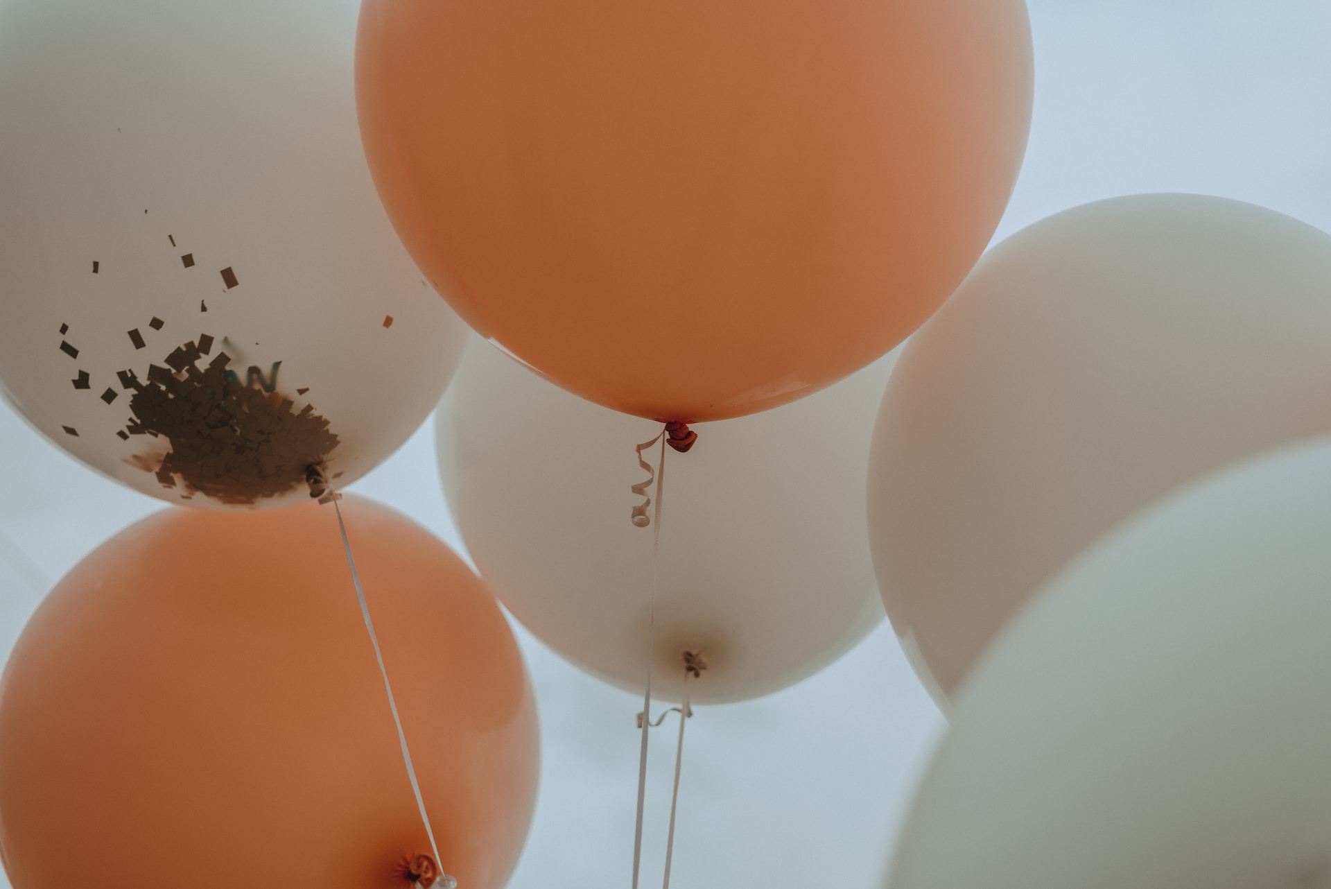 White and orange balloons containing gold confetti. 