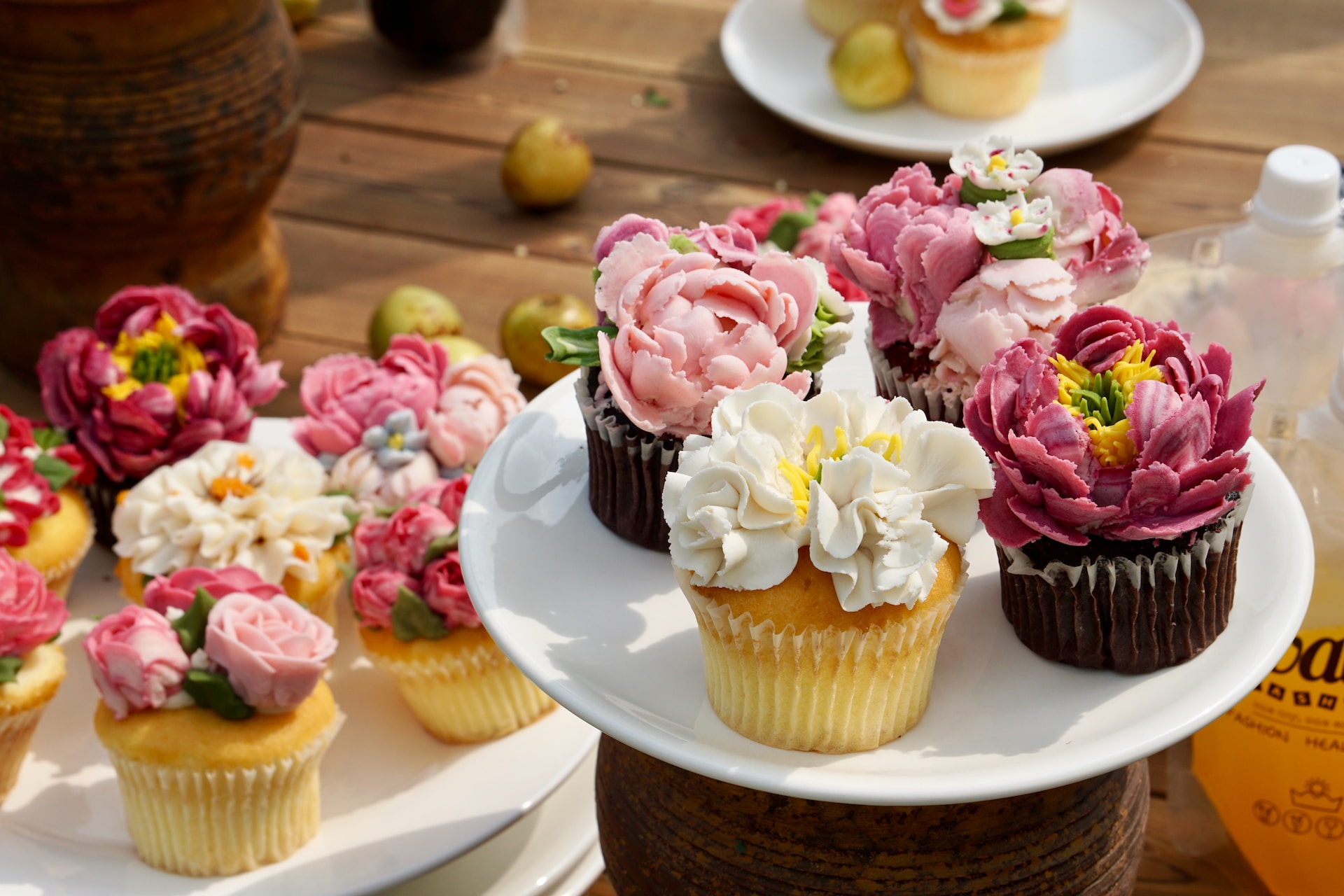 Two plates of vanilla and chocolate cupcakes with colourful floral icing.