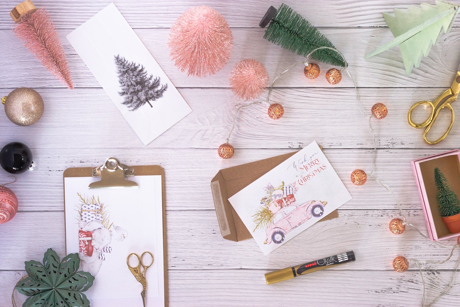 Christmas cards being written with Christmas baubles surrounding the stationary. 
