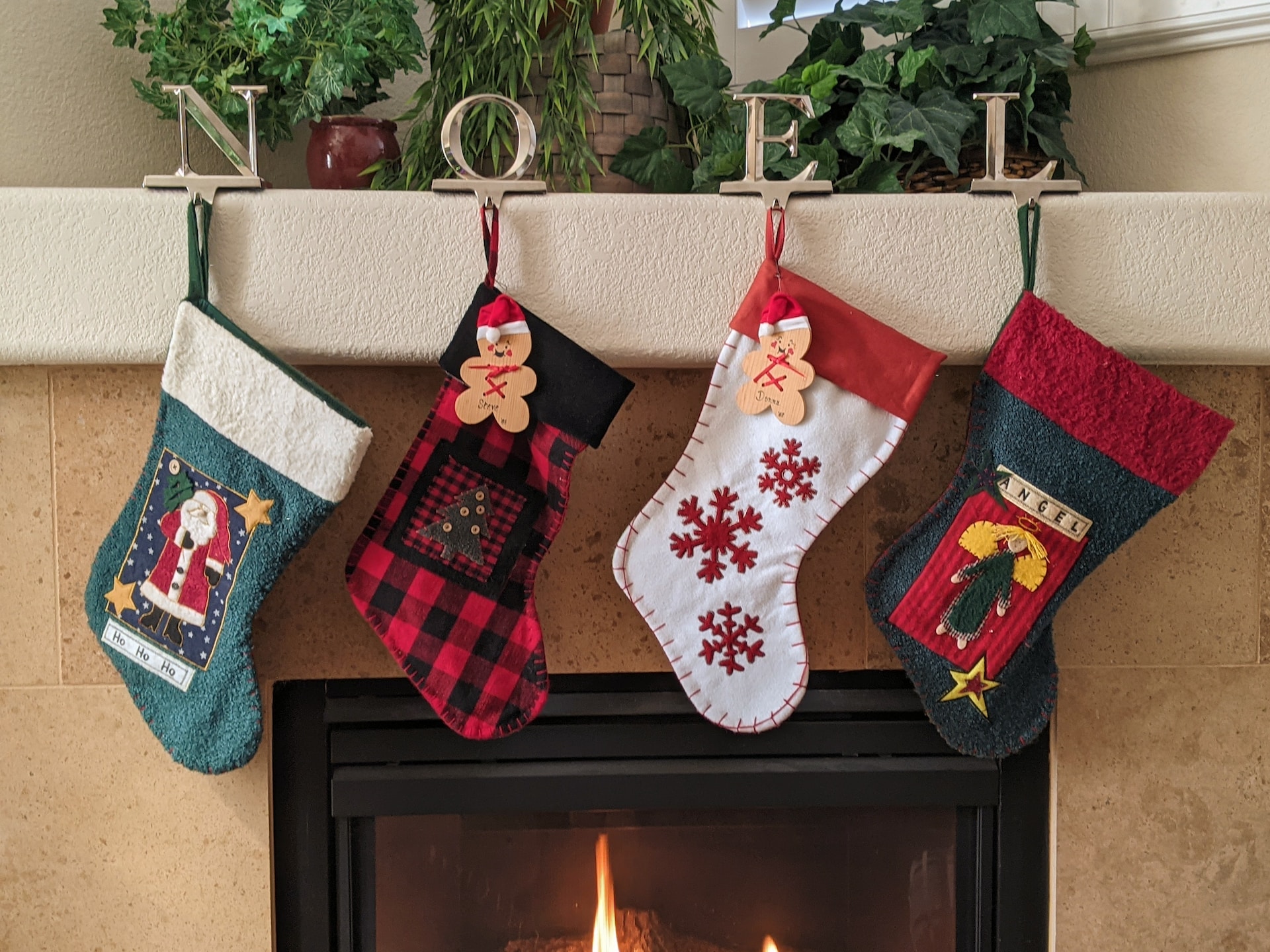 4 Stockings hung by the fireplace, underneath the word NOEL. 