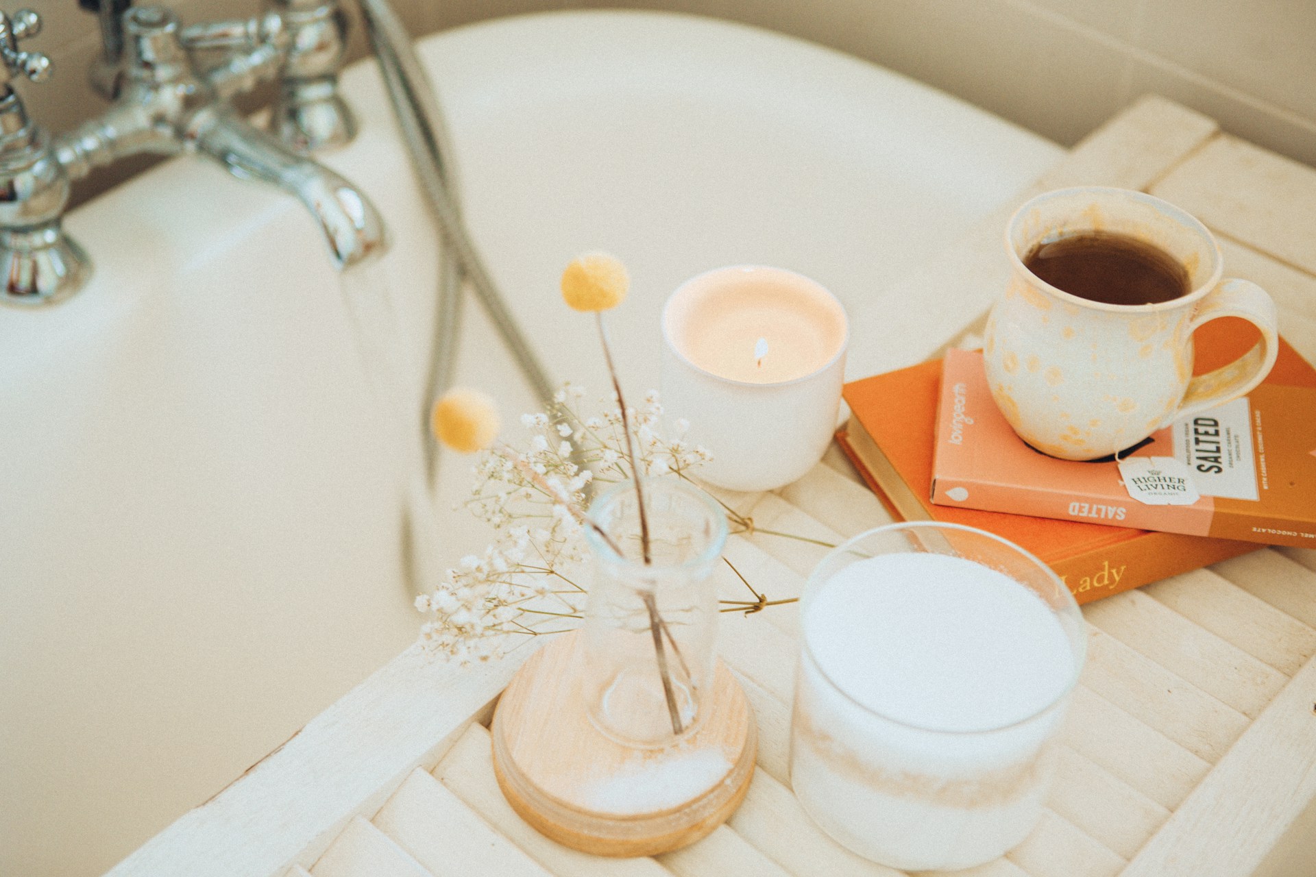 Bath with candles, tea and books beside. 