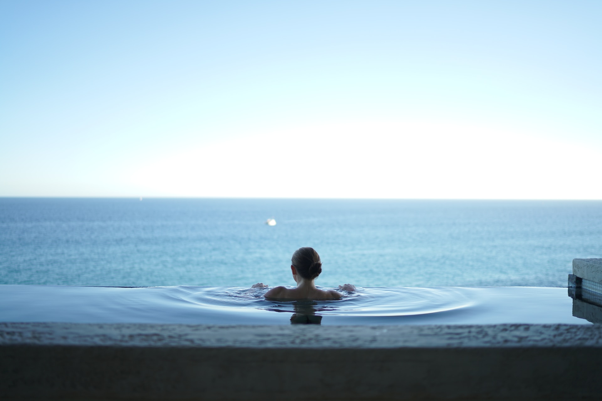 Woman looking out to sea from a pool. 