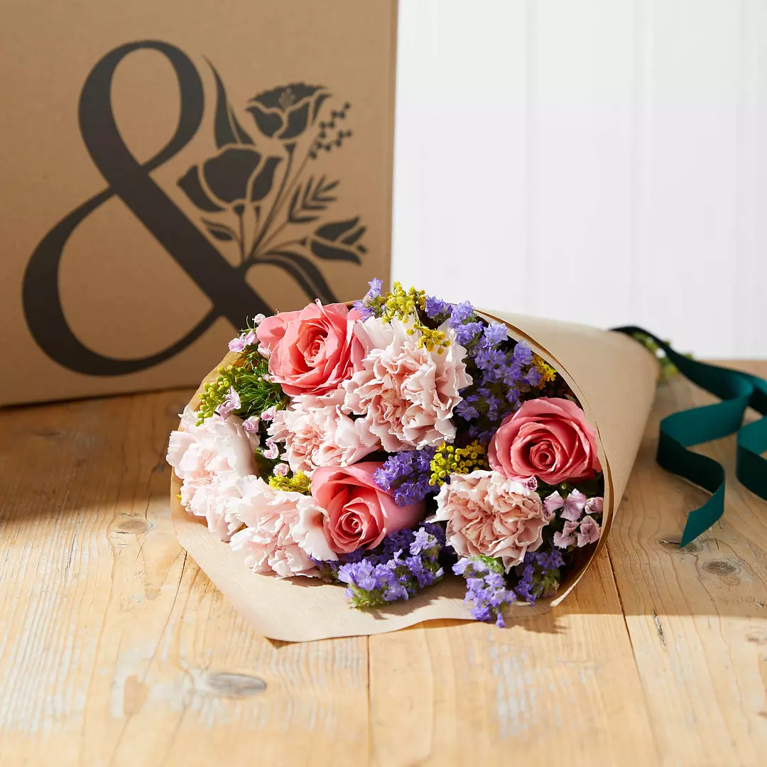 A Bloom & Wild bunch of roses and tulips wrapped in brown paper. 