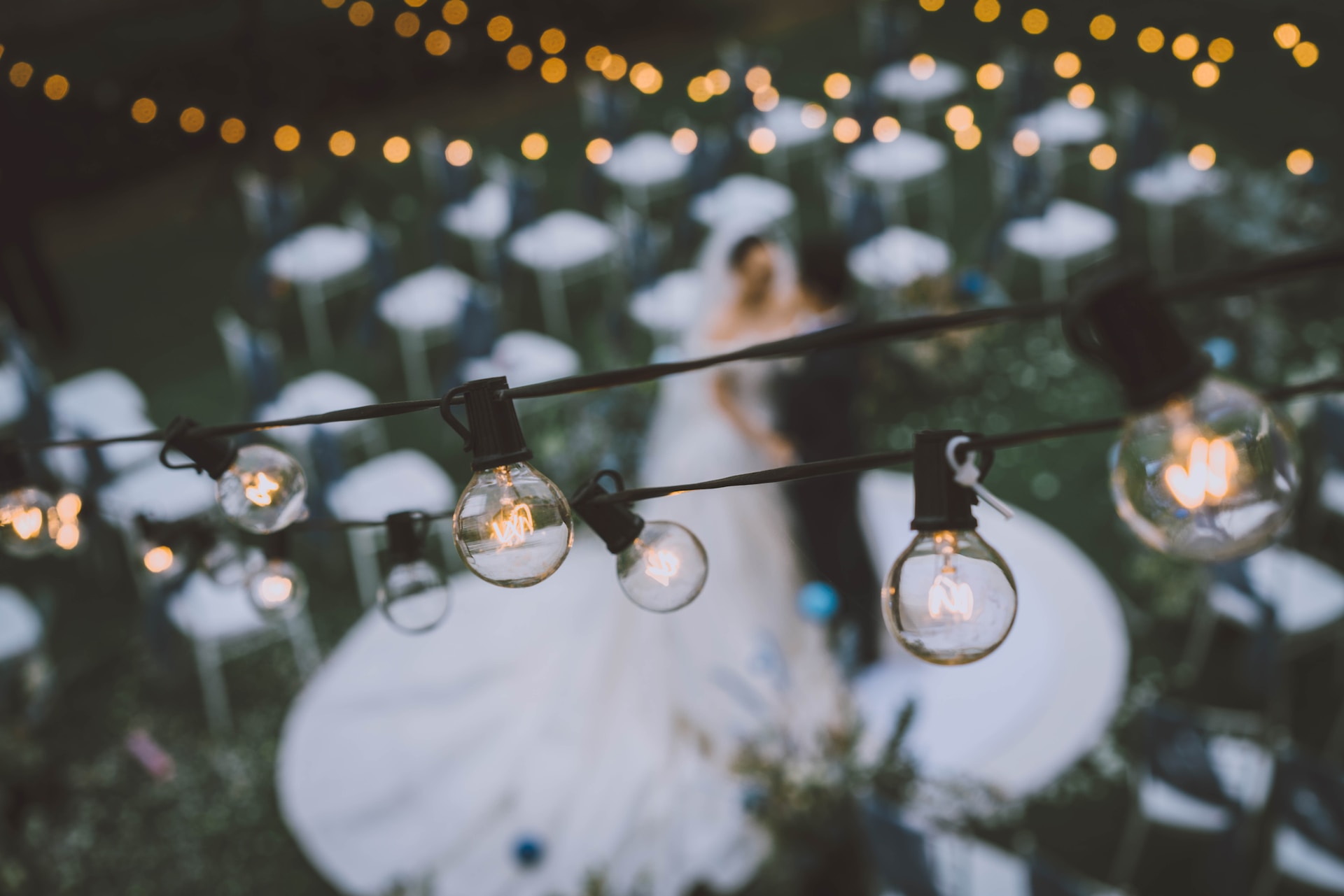 Bride and groom dancing under fairy lights outside. 