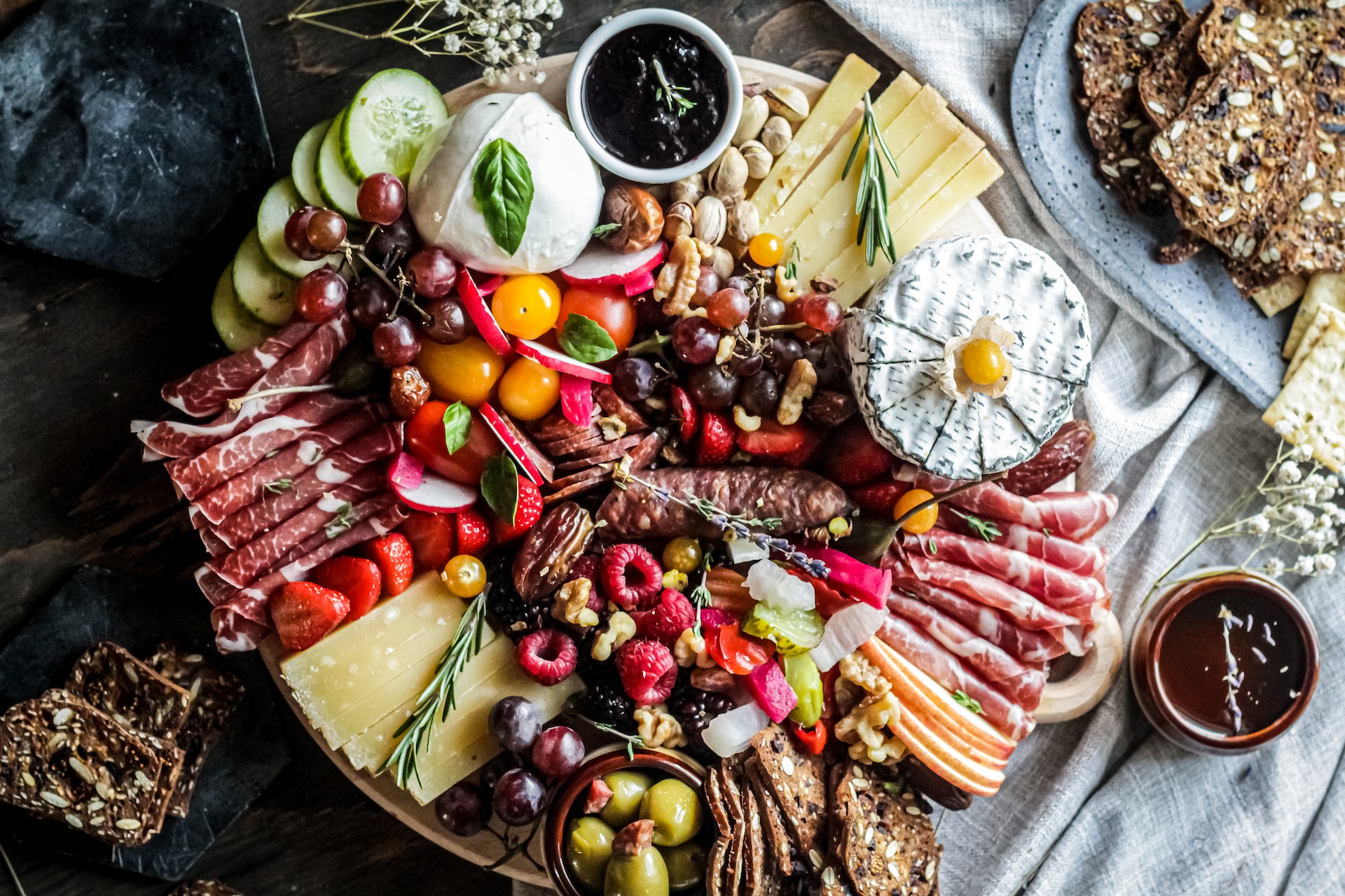 Selection of cheeses, grapes and crackers on a wooden board. 