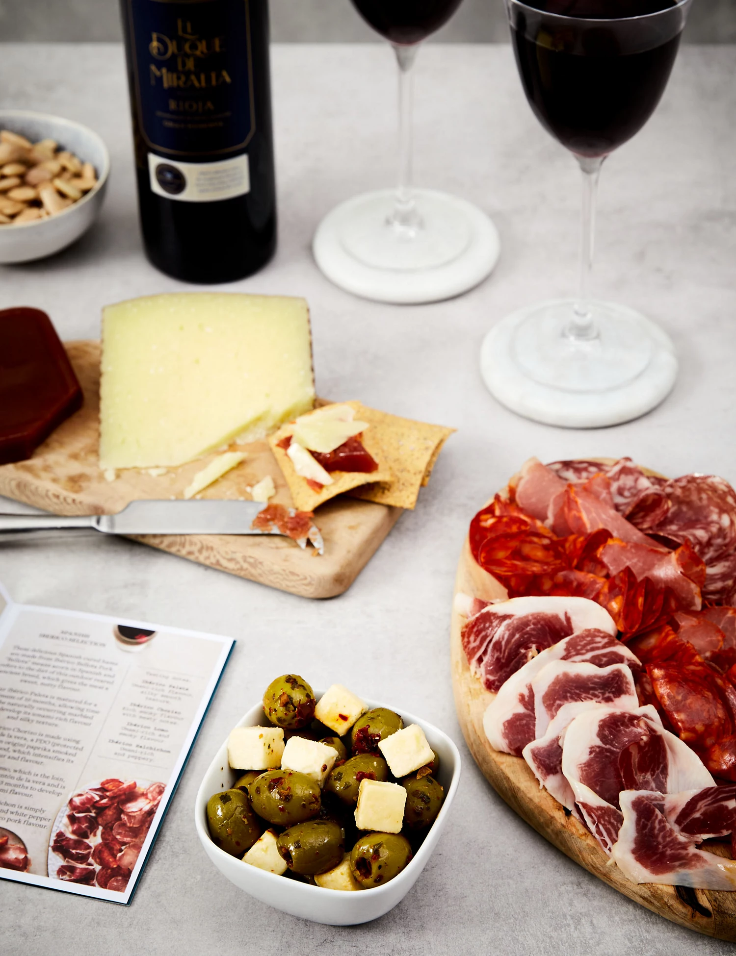 Cheese, cured meats, olives and wine on a marble tabletop. 