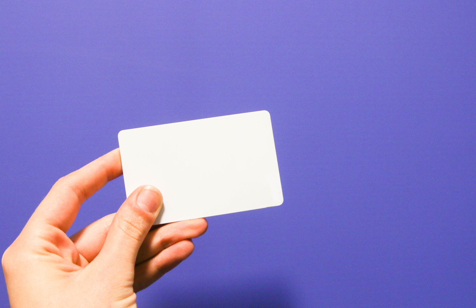 Hand presenting gift card on purple background. 