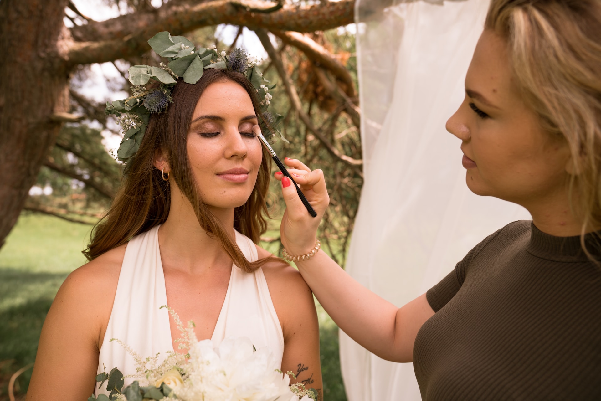 Bride getting makeup applied by makeup artist. 
