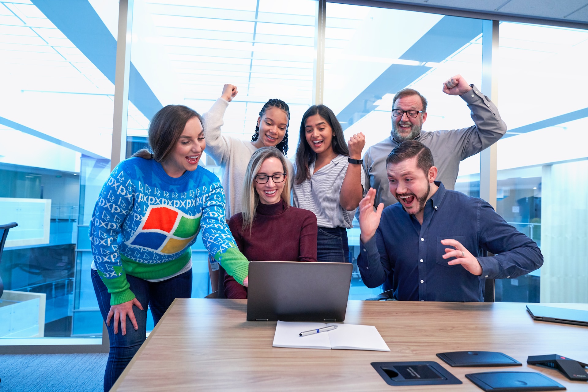 Group of colleagues celebrating around a laptop in an office. 