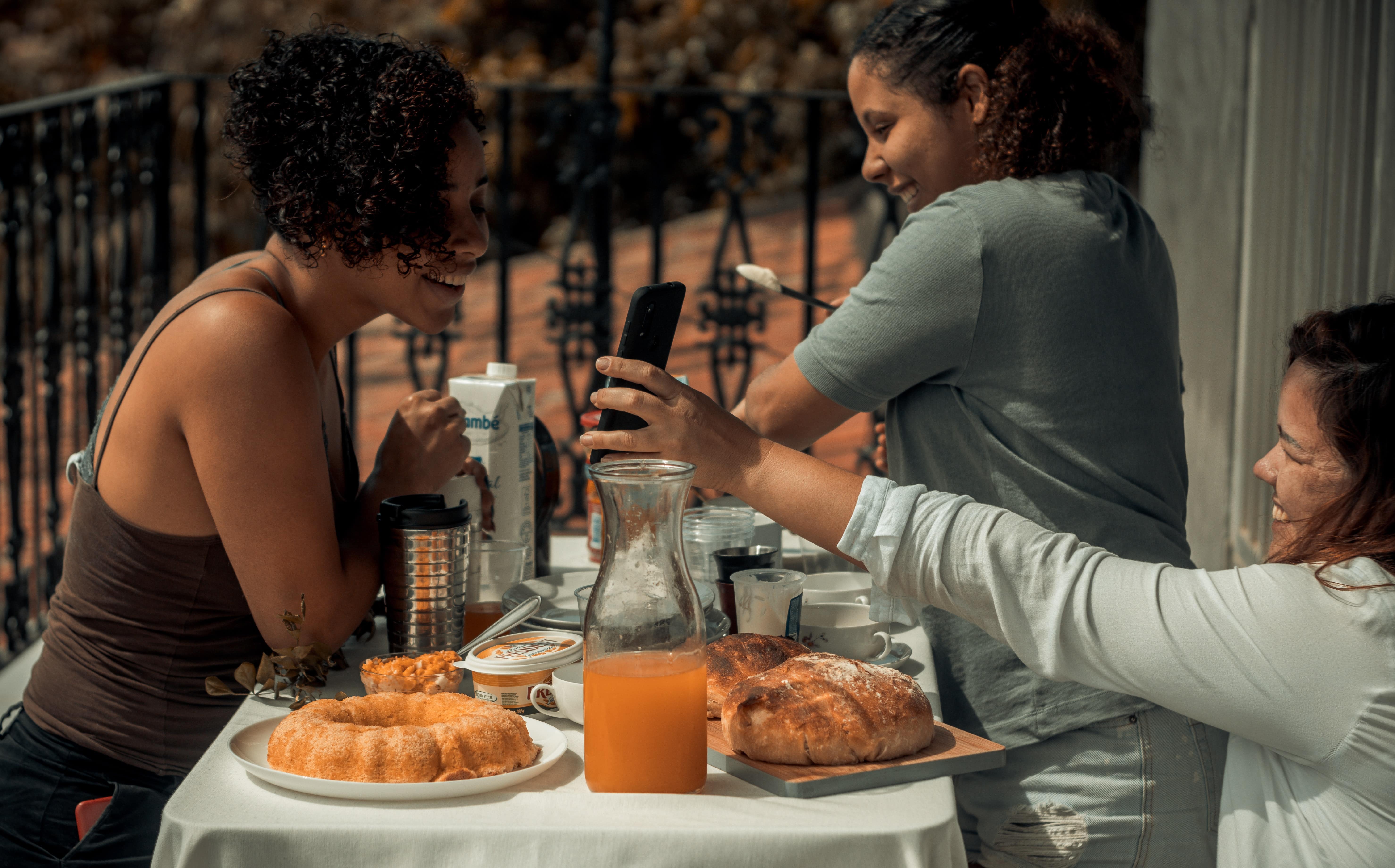 3 women sat on a terrace eating brunch together. 