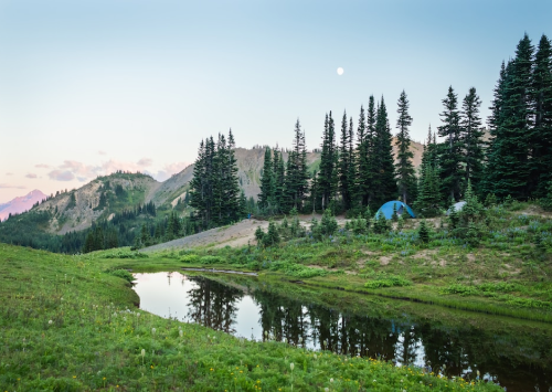 Camping in mountainous scenery beside a pond.